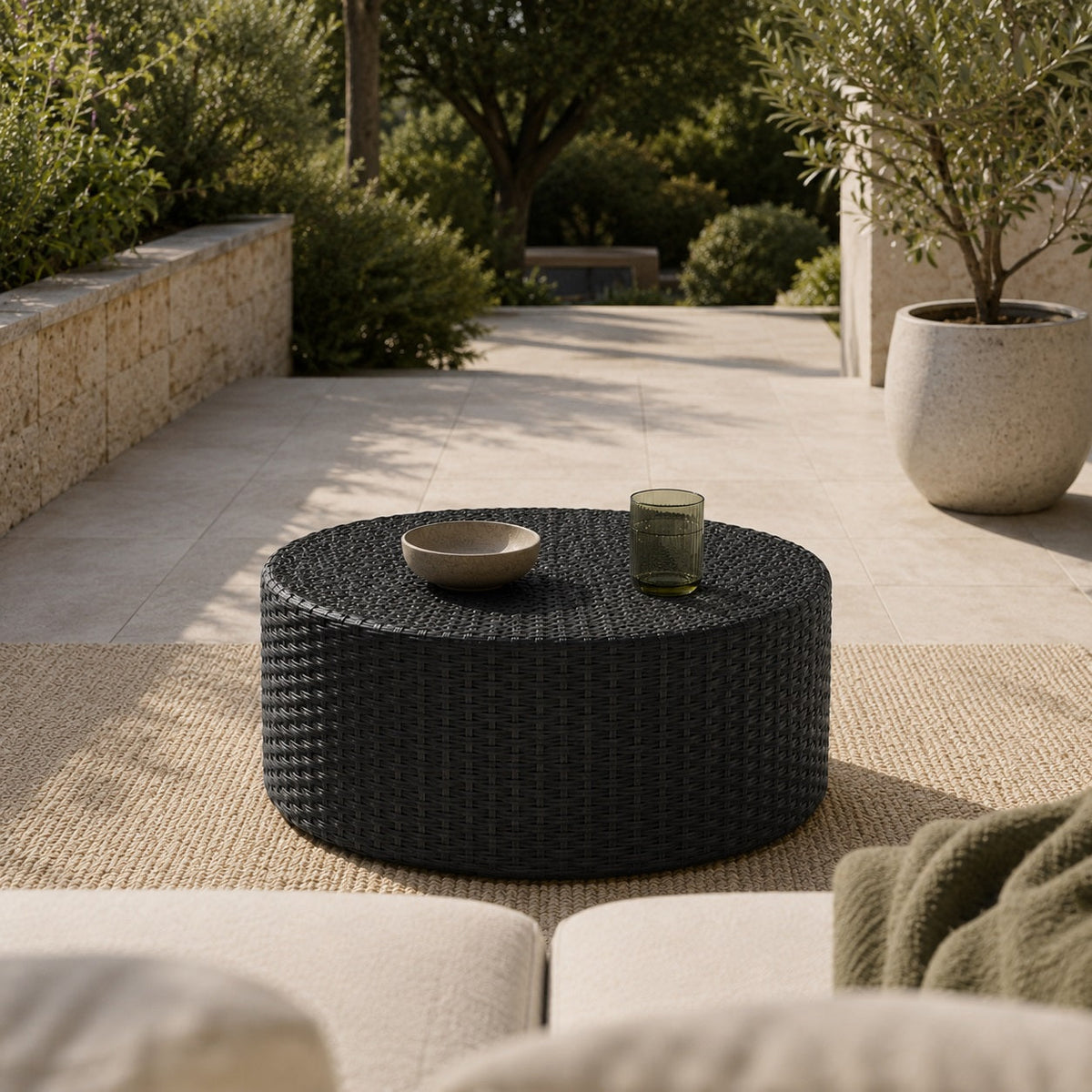 Table basse de jardin Oria noire ronde dans un espace d’extérieure contemporain et chaleureux