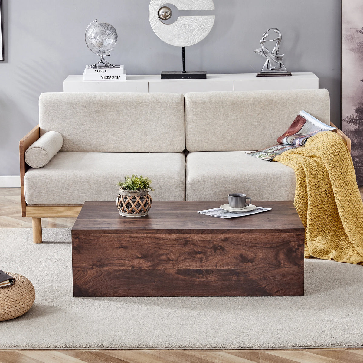 Table basse en noyer Novera, vue de face en situation dans un salon cosy avec plaid moutarde