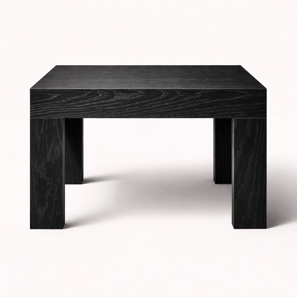 Table basse noire de salon au design structuré, plateau épais et piètement massif pour un intérieur moderne.