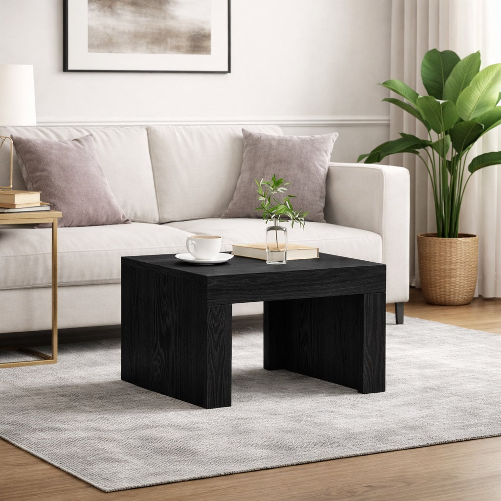 Table basse noire de salon en finition noire, intégrée dans un salon lumineux avec canapé clair et décor minimaliste.